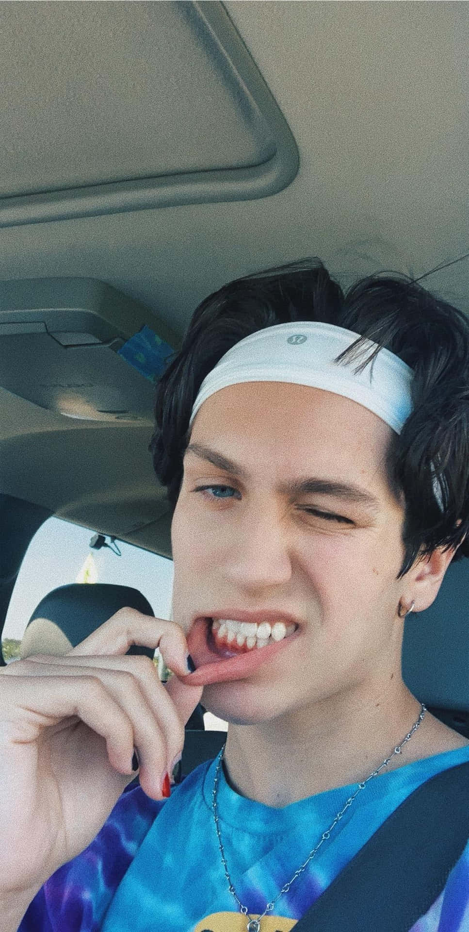 A Young Man Is Sitting In A Car And Is Chewing His Tongue