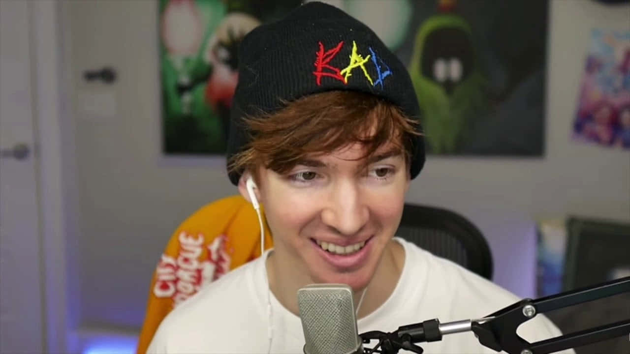 A Young Man Is Smiling While Holding A Microphone Background