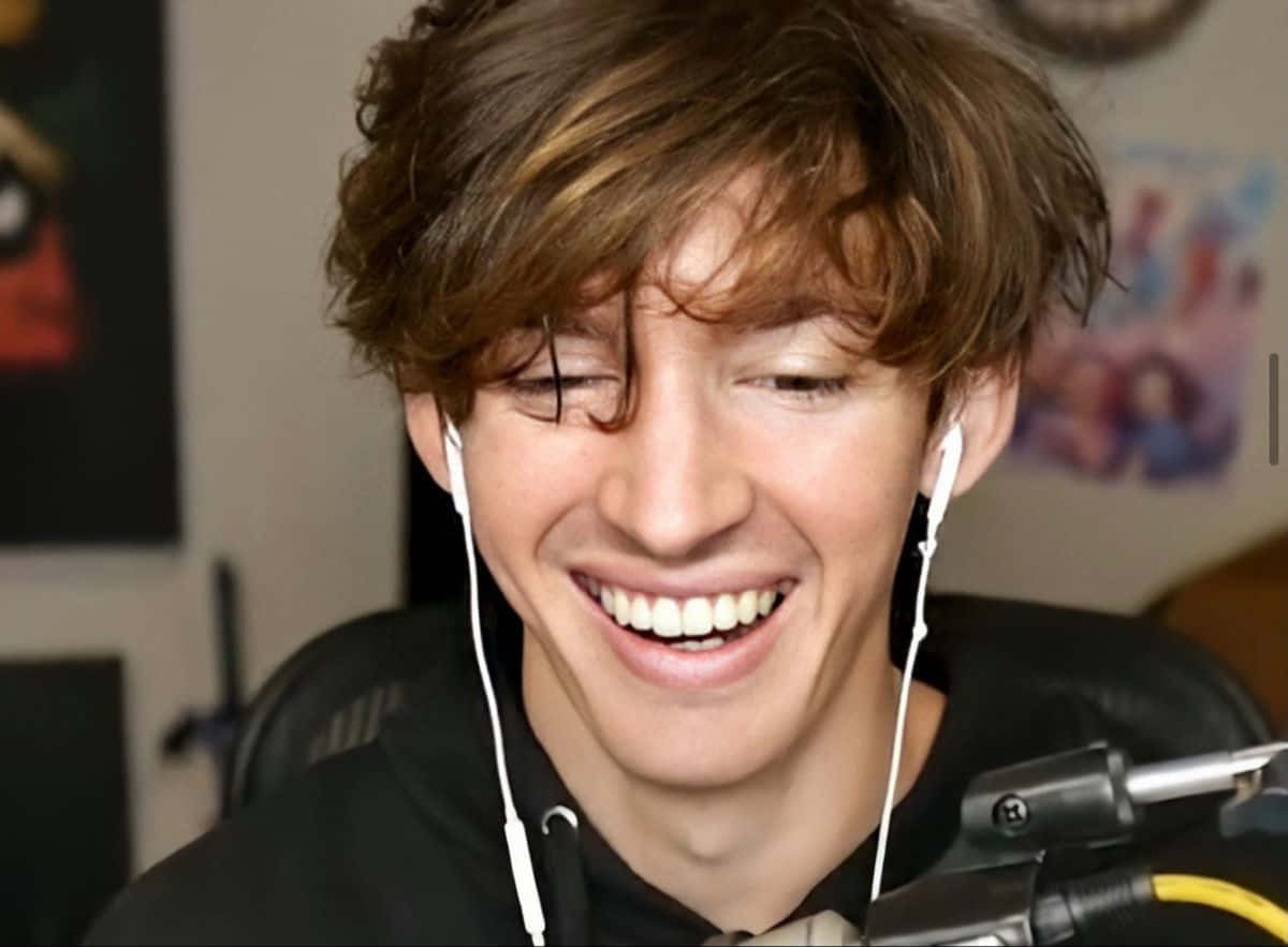 A Young Man Is Smiling While Wearing Headphones Background