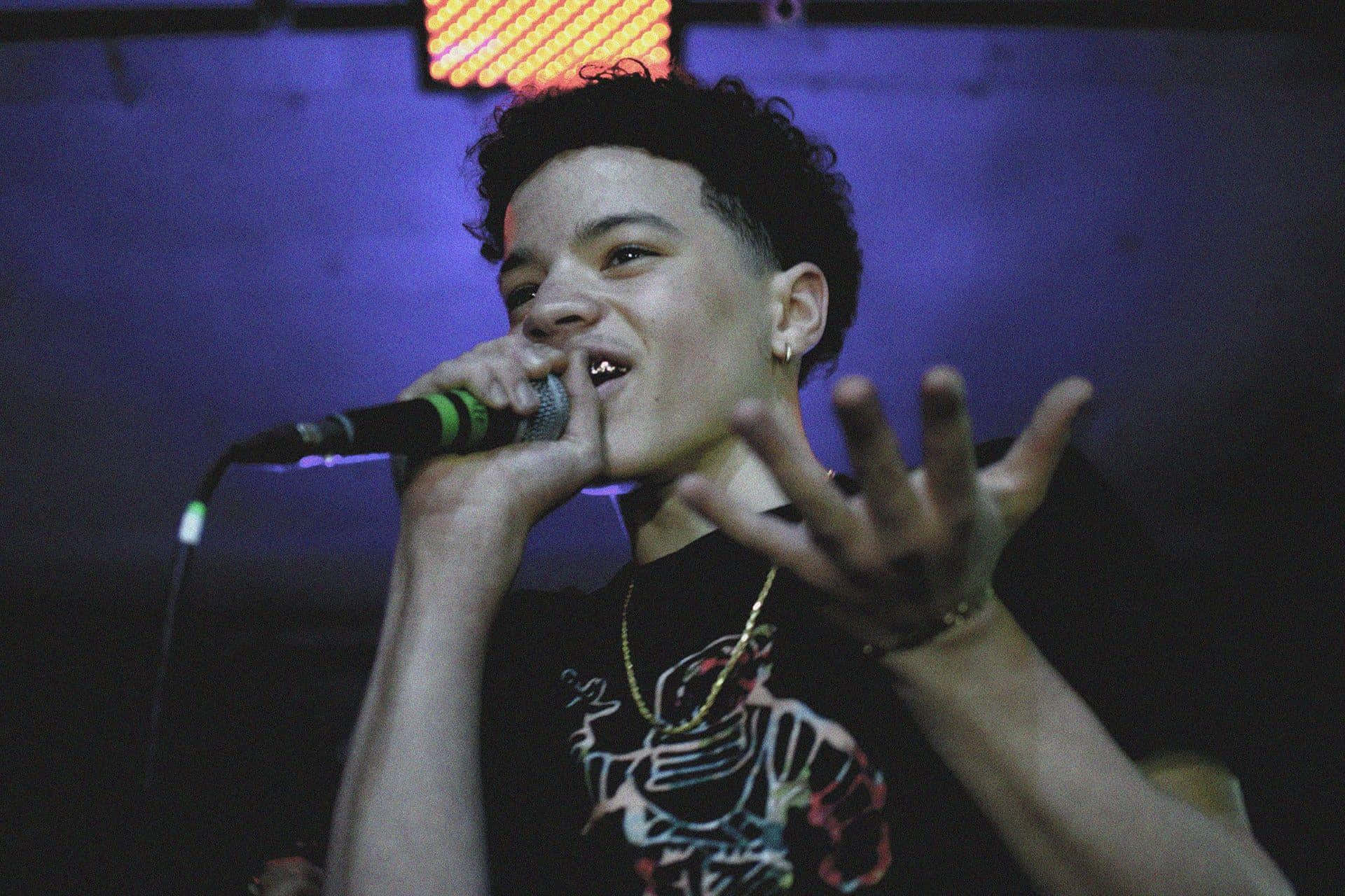 A Young Man Singing Into A Microphone