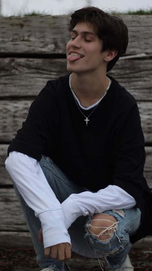 A Young Man Sitting On A Wooden Bench Background