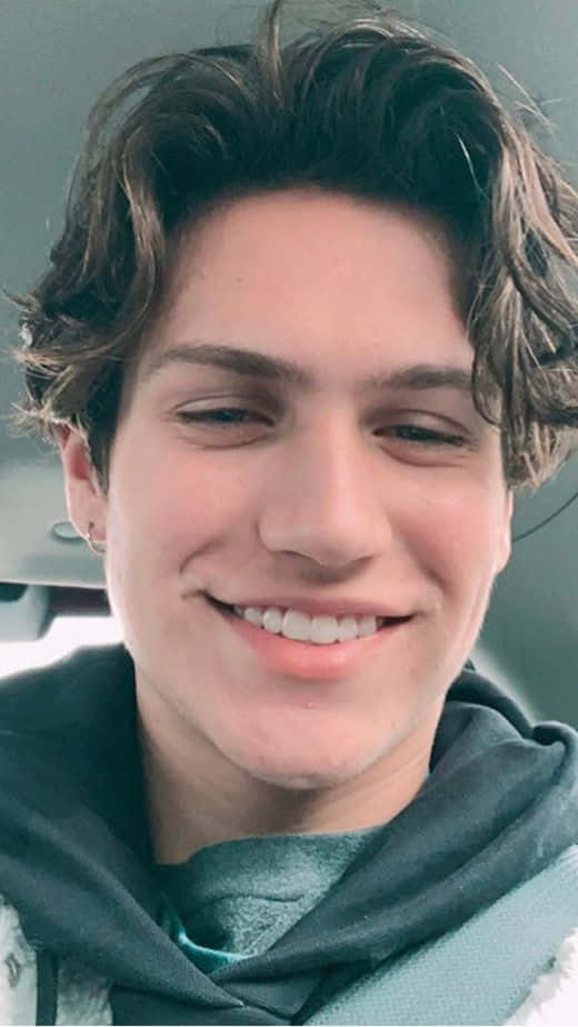 A Young Man Smiling In A Car Background