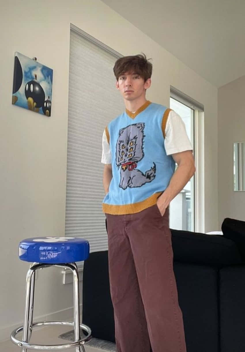 A Young Man Standing In Front Of A Couch Background