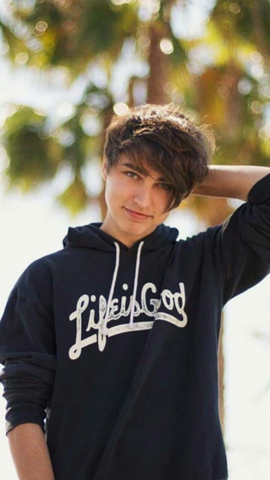 A Young Man Wearing A Black Hoodie With The Word Lifegod On It Background