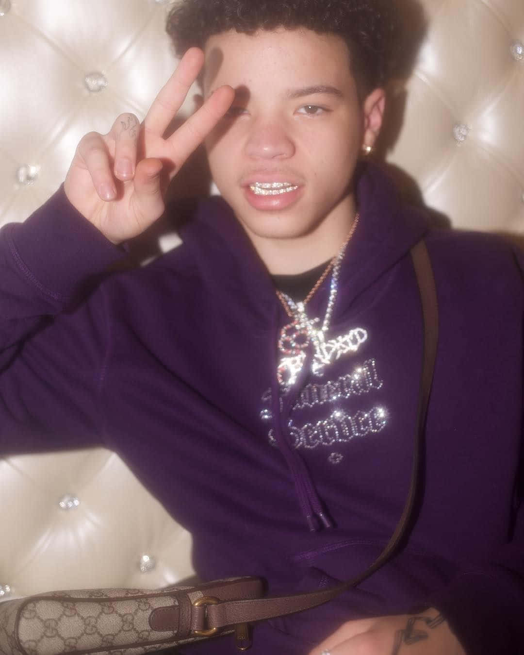 A Young Man Wearing A Purple Hoodie And A Purse Background