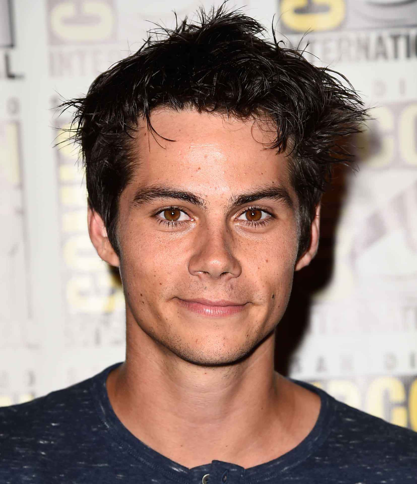 A Young Man With Dark Hair And Blue Shirt Background