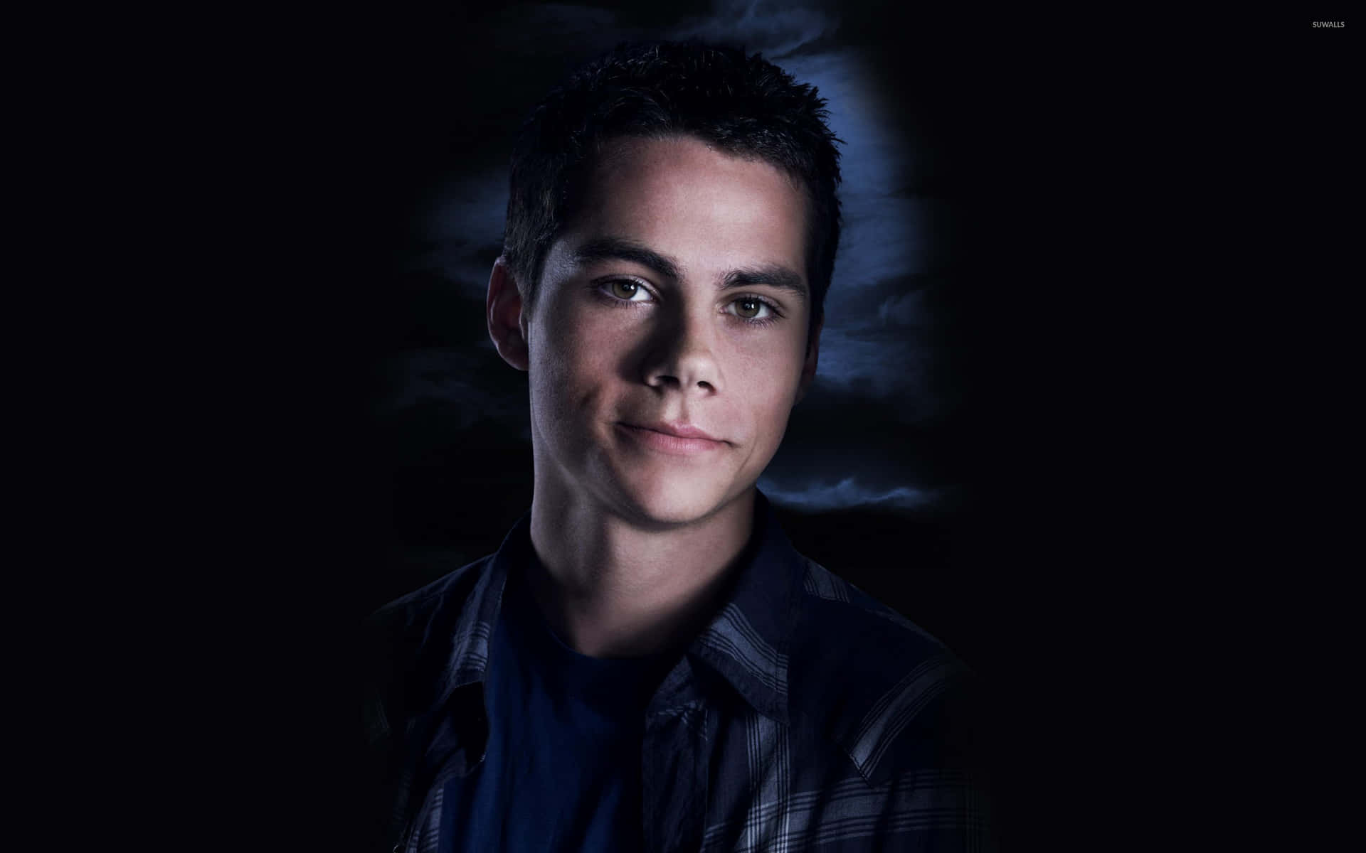 A Young Man With Dark Hair And Blue Shirt Background