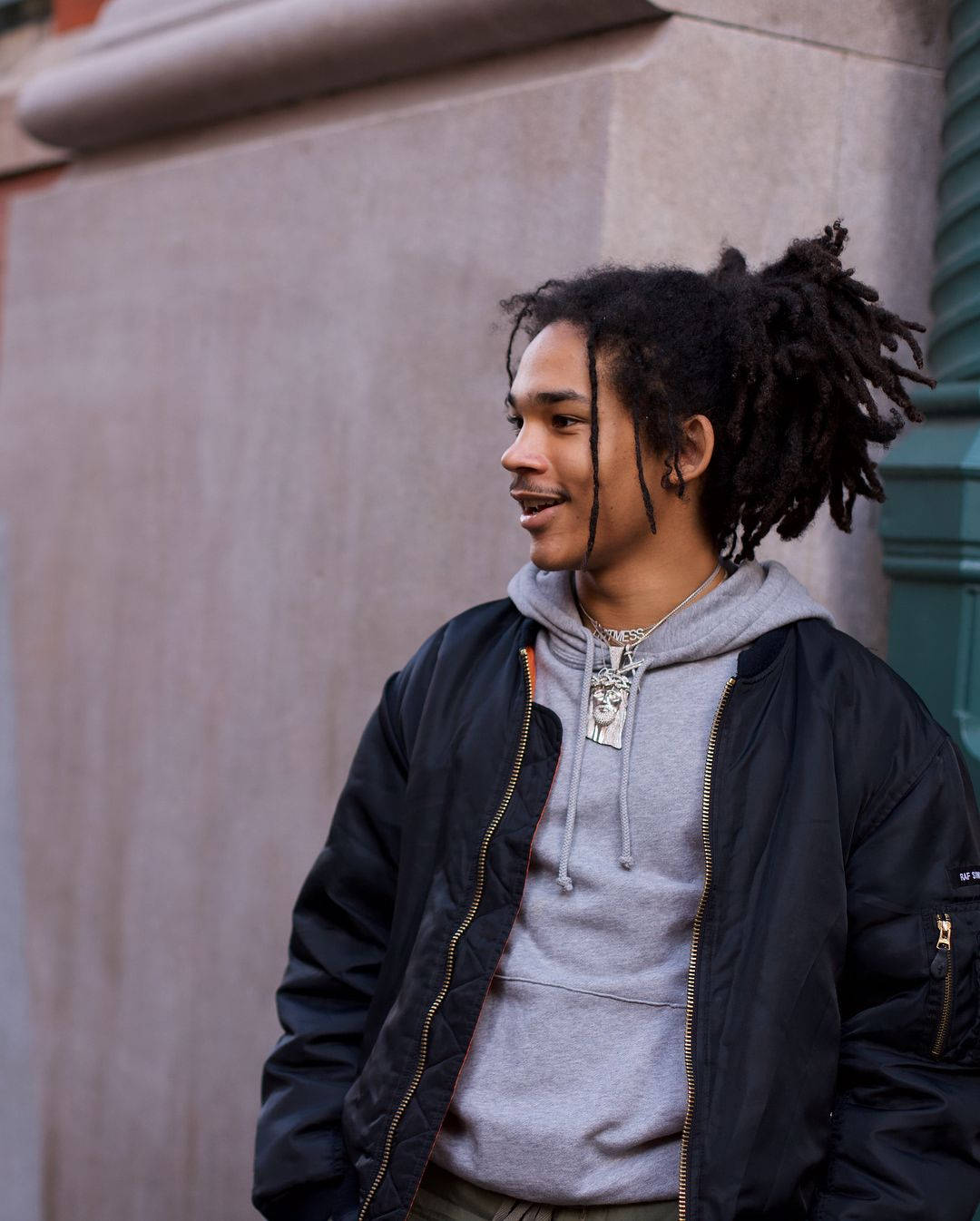 A Young Man With Dreadlocks Standing On A Street Background