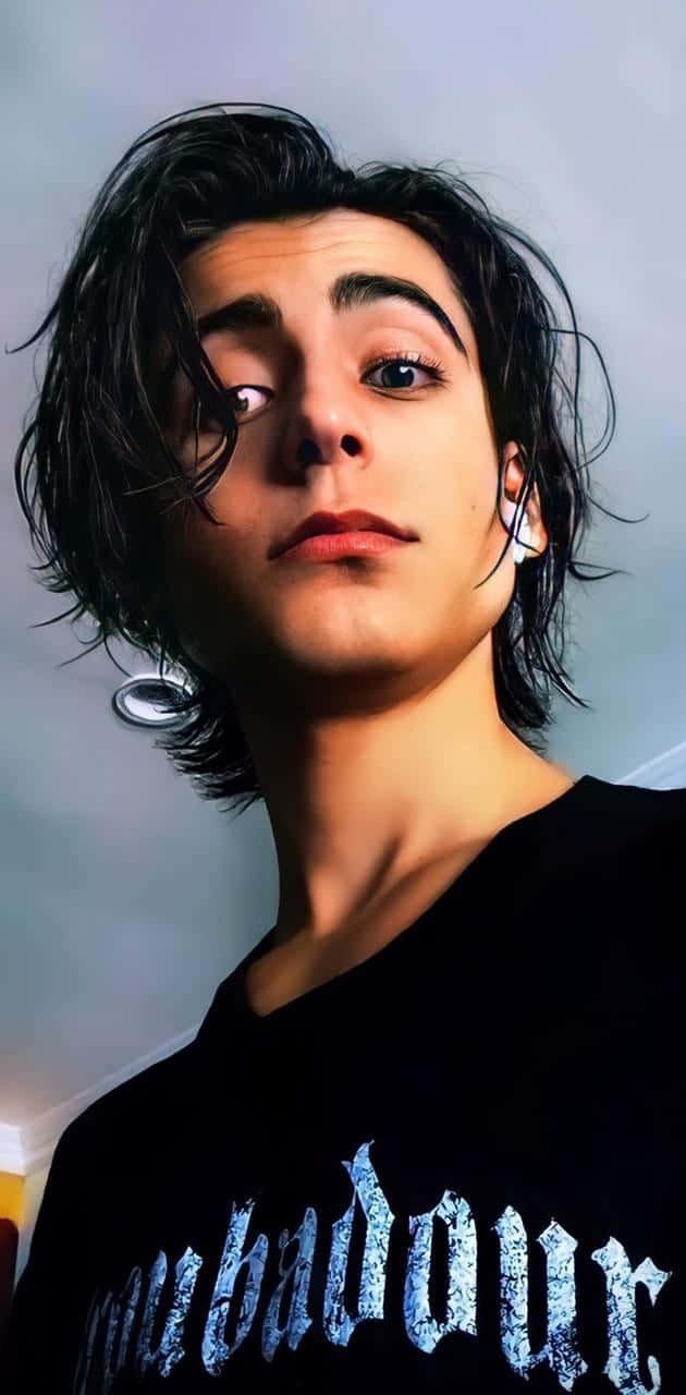 A Young Man With Long Hair And A Black Shirt Background