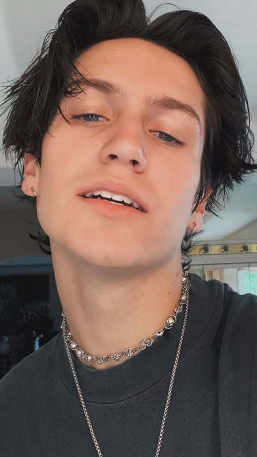 A Young Man With Long Hair And A Necklace Background