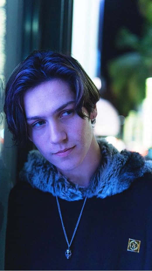 A Young Man With Long Hair And A Necklace Background