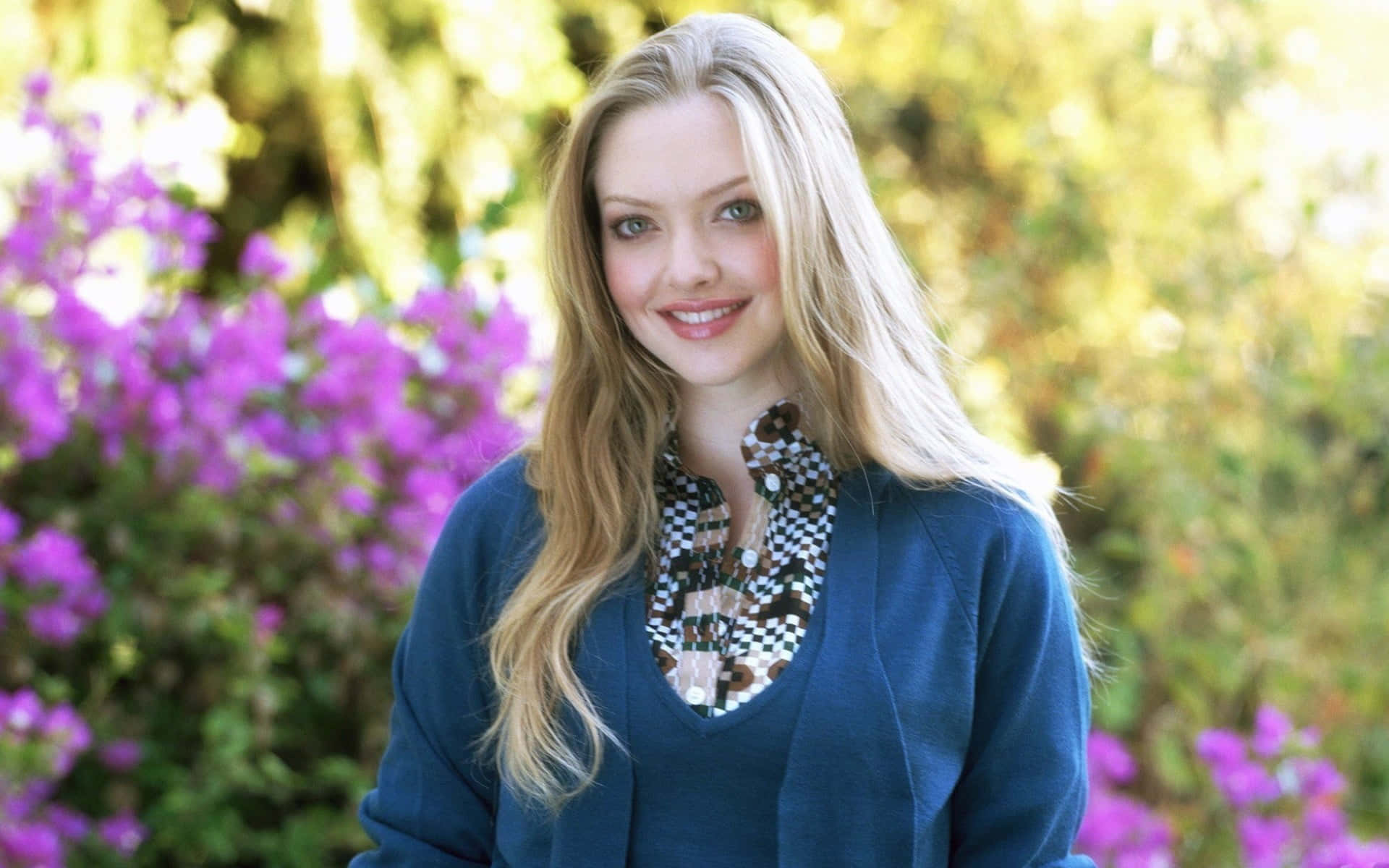 A Young Woman In A Blue Cardigan Standing In Front Of Flowers Background