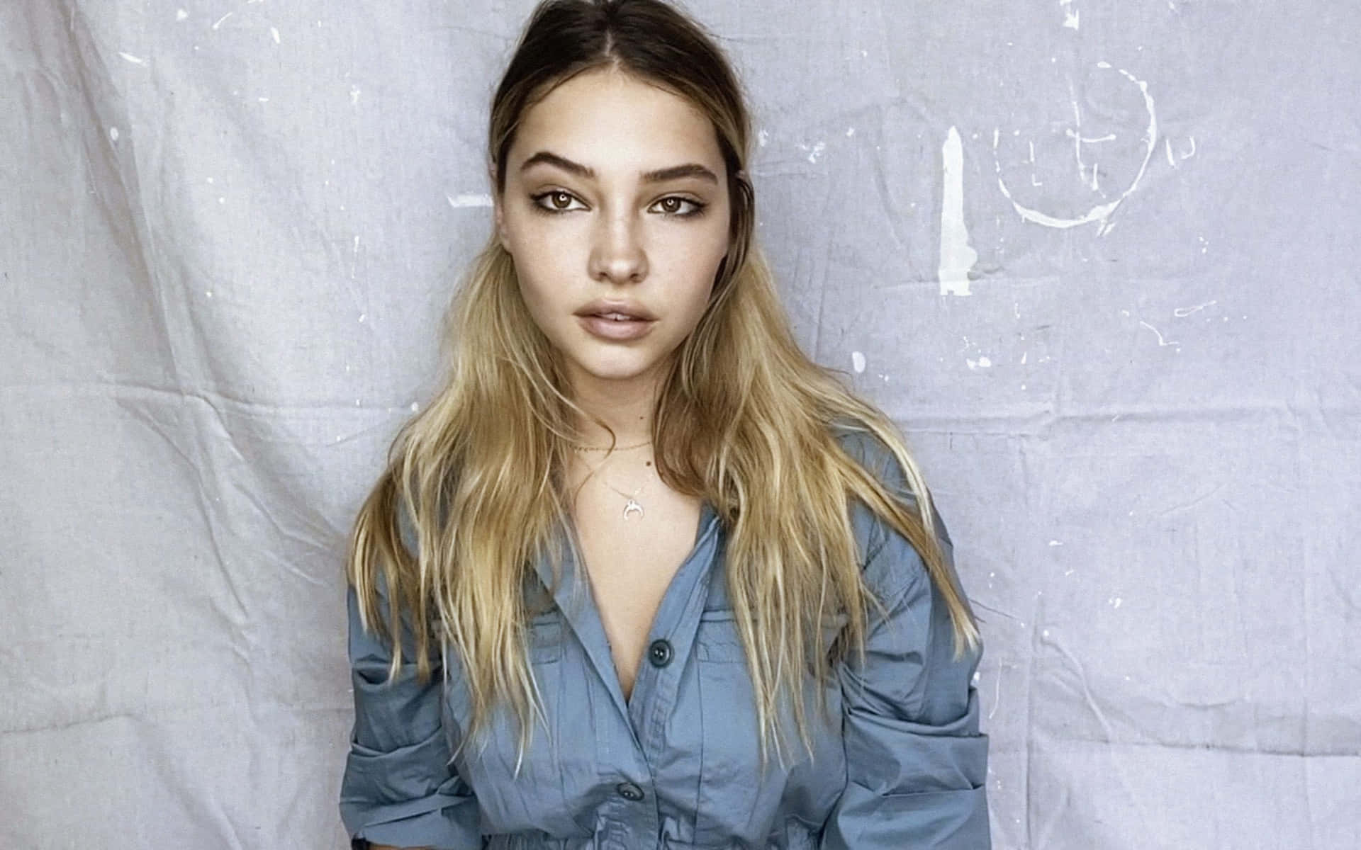 A Young Woman In A Blue Shirt Posing For A Photo Background