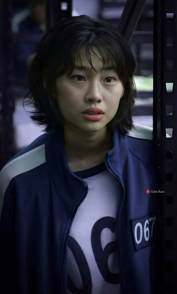 A Young Woman In A Blue Shirt Standing In A Jail Cell Background