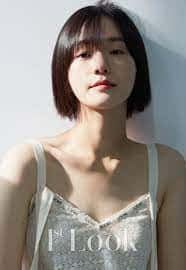 A Young Woman In A White Dress Posing Against A Wall Background