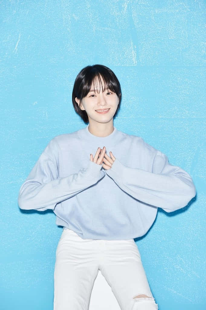 A Young Woman Sitting On A Blue Wall Background