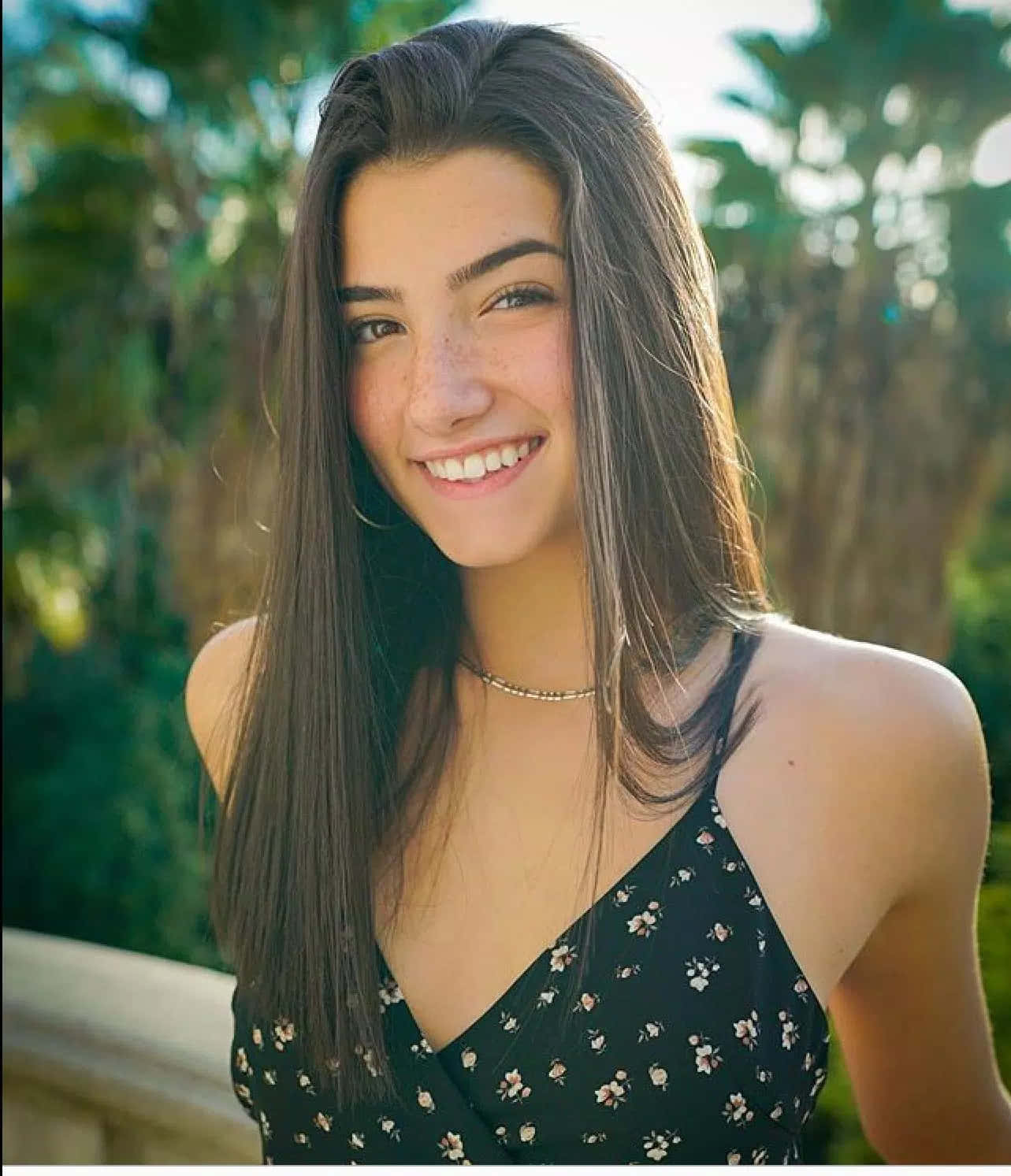 A Young Woman Smiling In Front Of Palm Trees Background