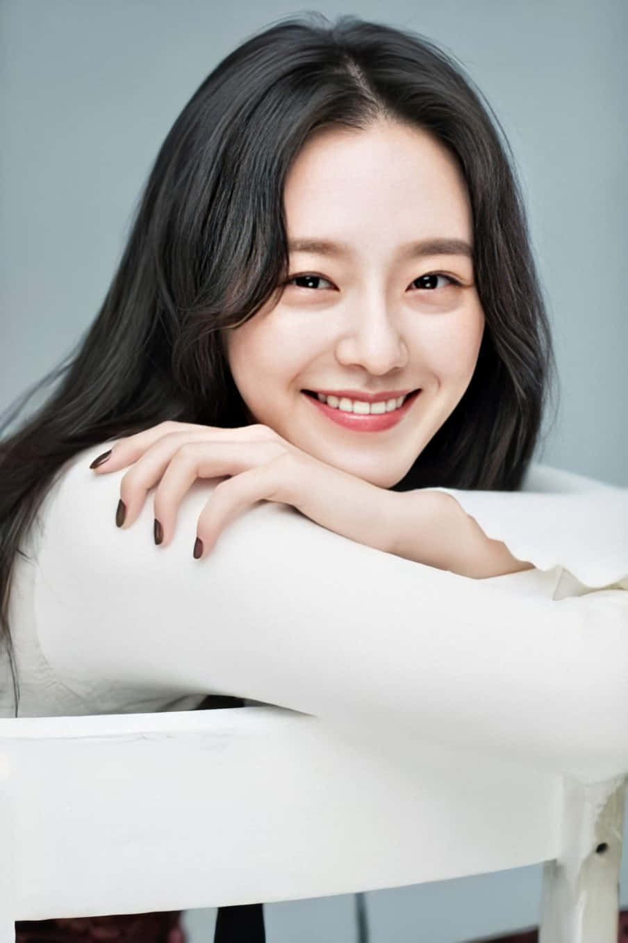 A Young Woman Smiling While Sitting On A Chair Background