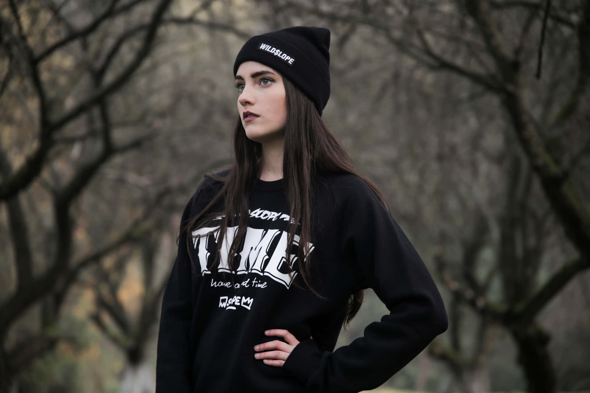 A Young Woman Wearing A Black Sweatshirt And Beanie Background