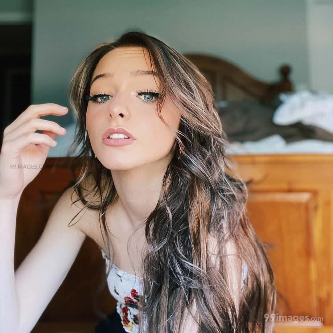 A Young Woman With Long Hair Posing On A Bed Background