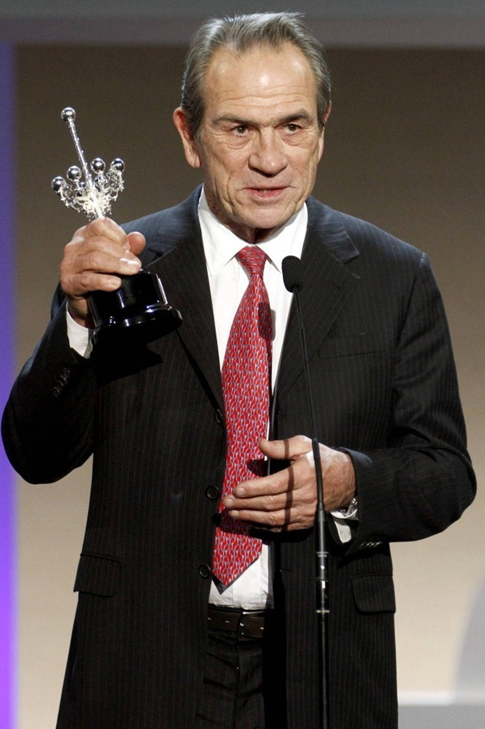 Acclaimed Actor Tommy Lee Jones Grasping A Trophy Background