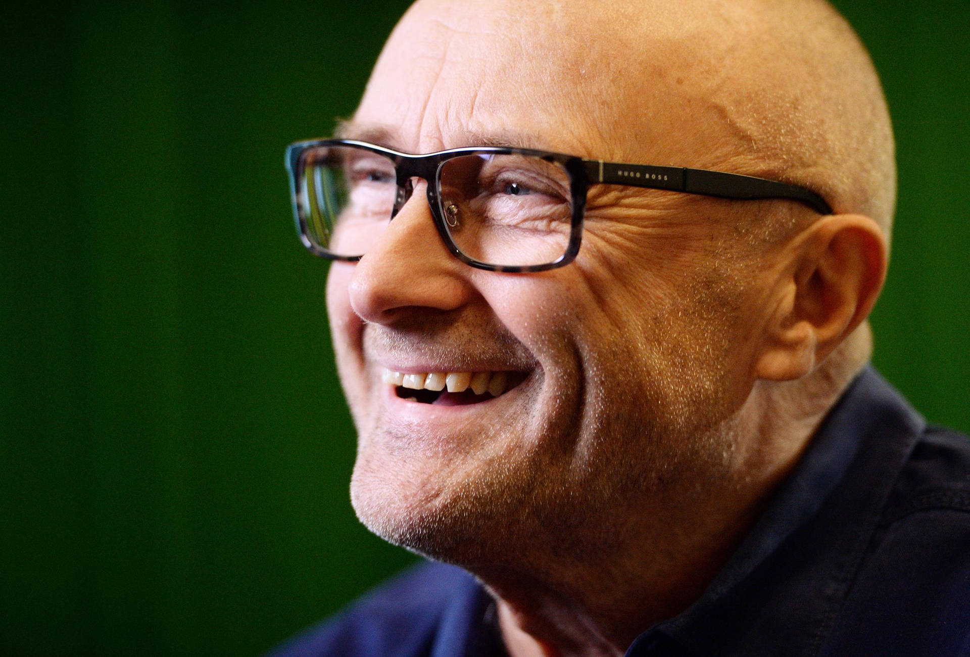 Acclaimed British Songwriter Phil Collins Smiling For A Portrait. Background