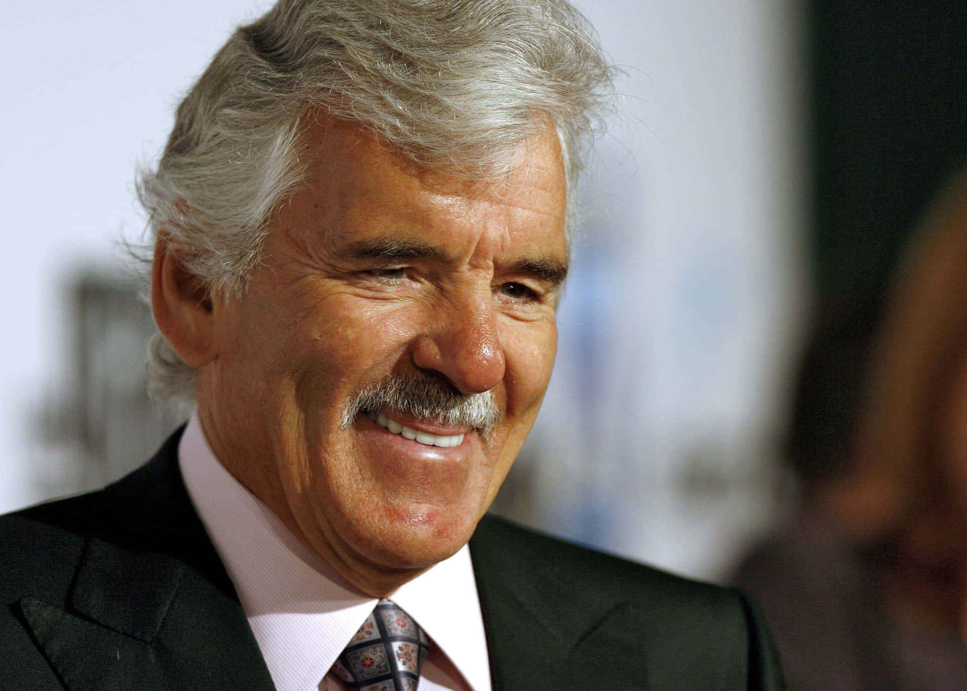 Actor Dennis Farina Posing In An Elegant Suit. Background