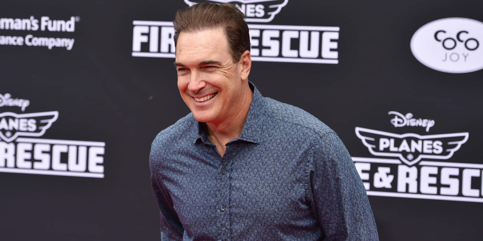 Actor Patrick Warburton Striking An Animated Pose Background