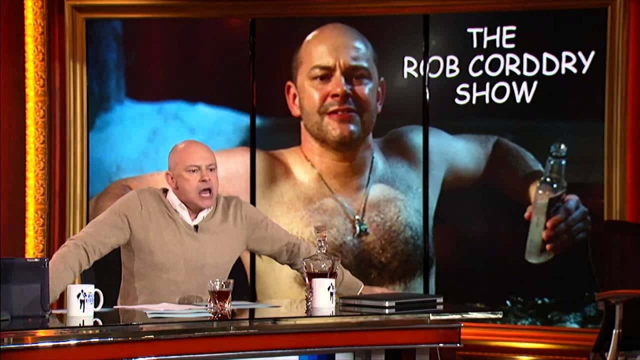 Actor Rob Corddry Entertaining An Audience With Humorous Anecdotes Background