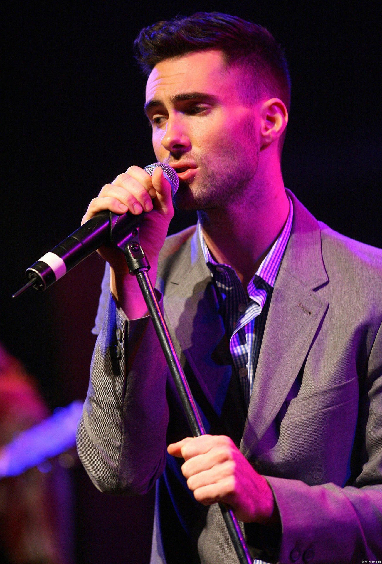 Adam Levine Radiating Charm In A Grey Suit Background
