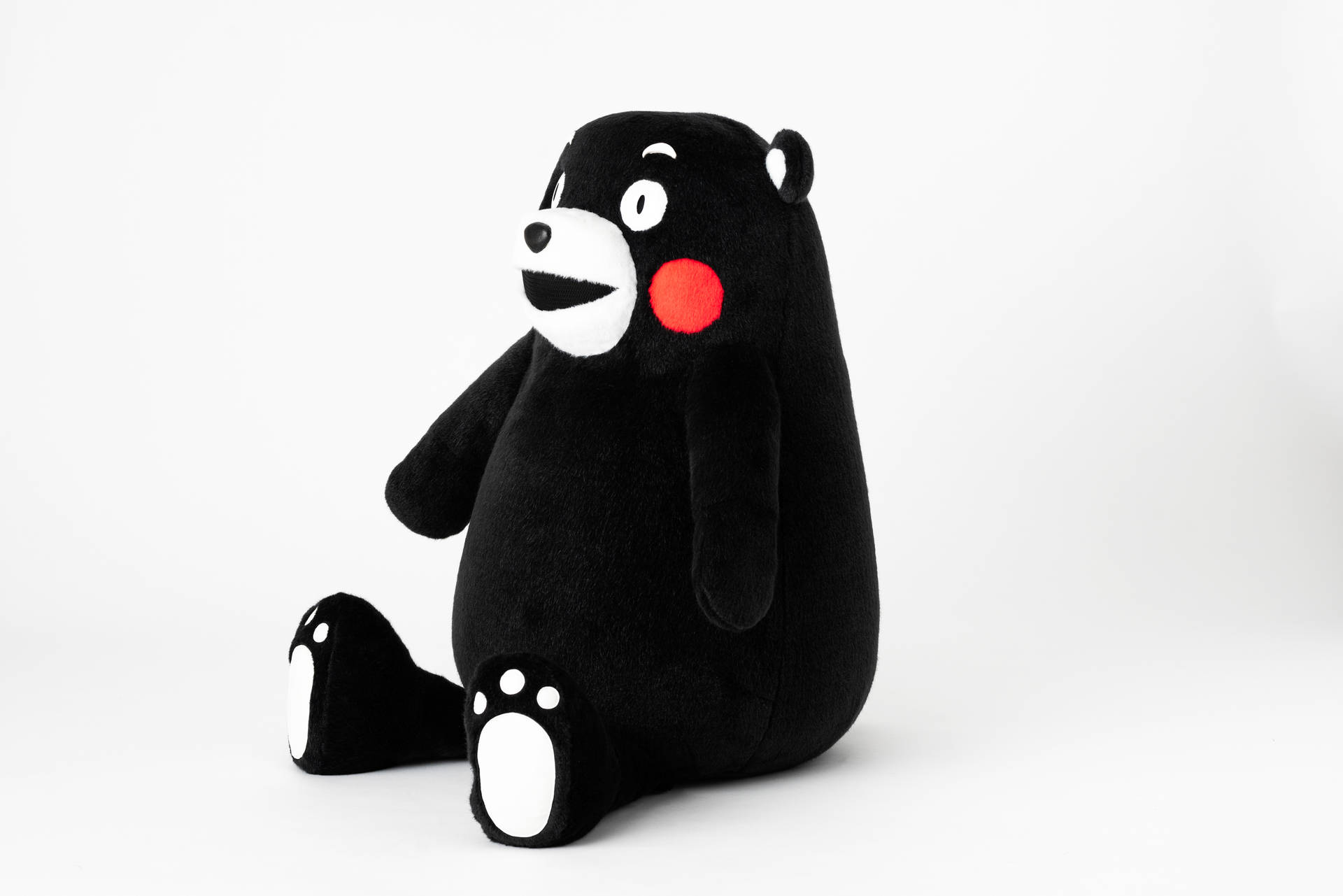 Adorable Kumamon Bear Plushie Sitting Comfortably Background