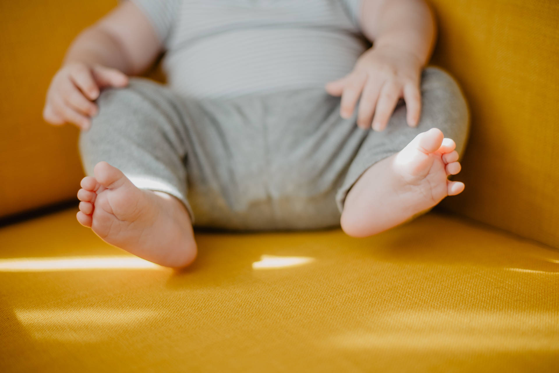 Adorable Newborn Baby Girl Seated In A Yellow Chair Background