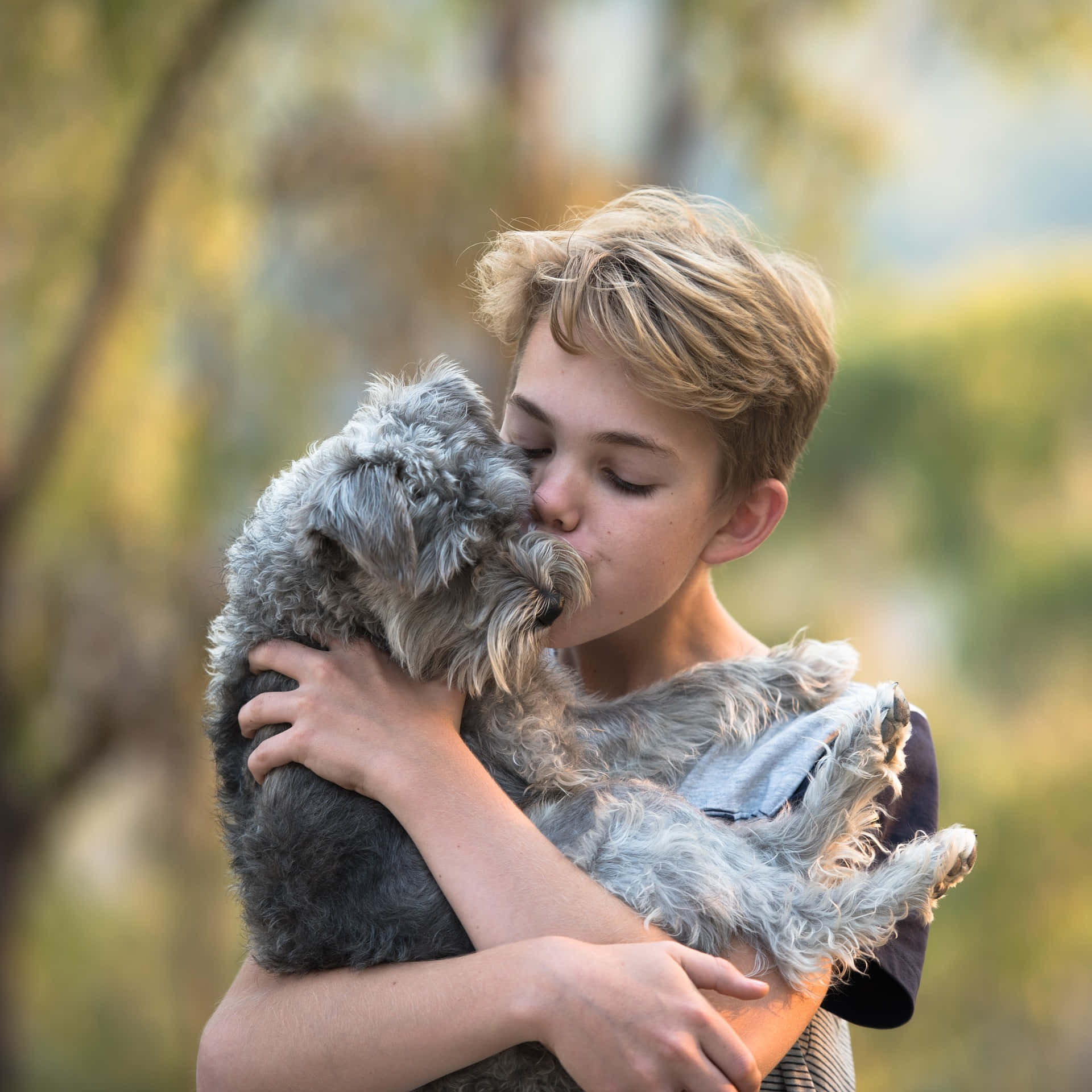 Adorable Photo Of A Young Boy Embracing And Kissing His Tangible Dog Background
