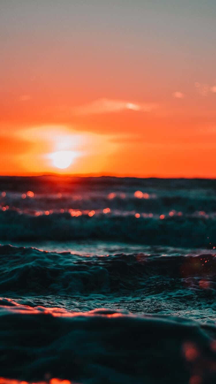 Aesthetic Sunset Iphone Of Sun Reflecting On Ocean Waves Background