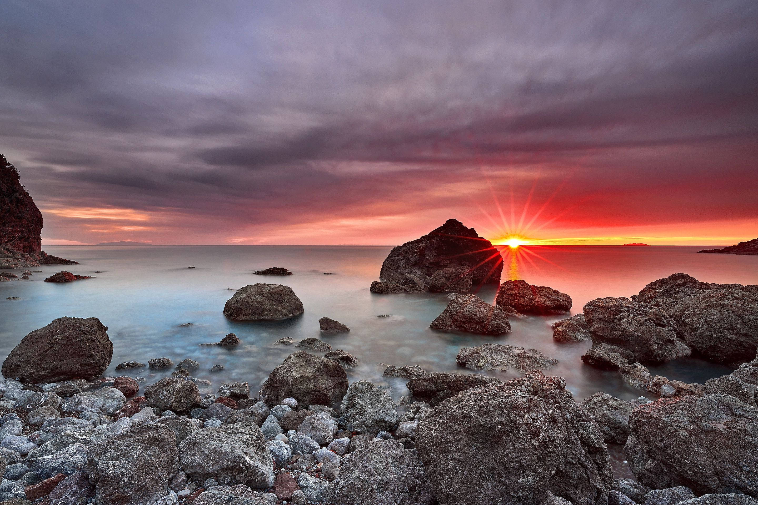 Aesthetic Sunset Over Rocky Ocean Background