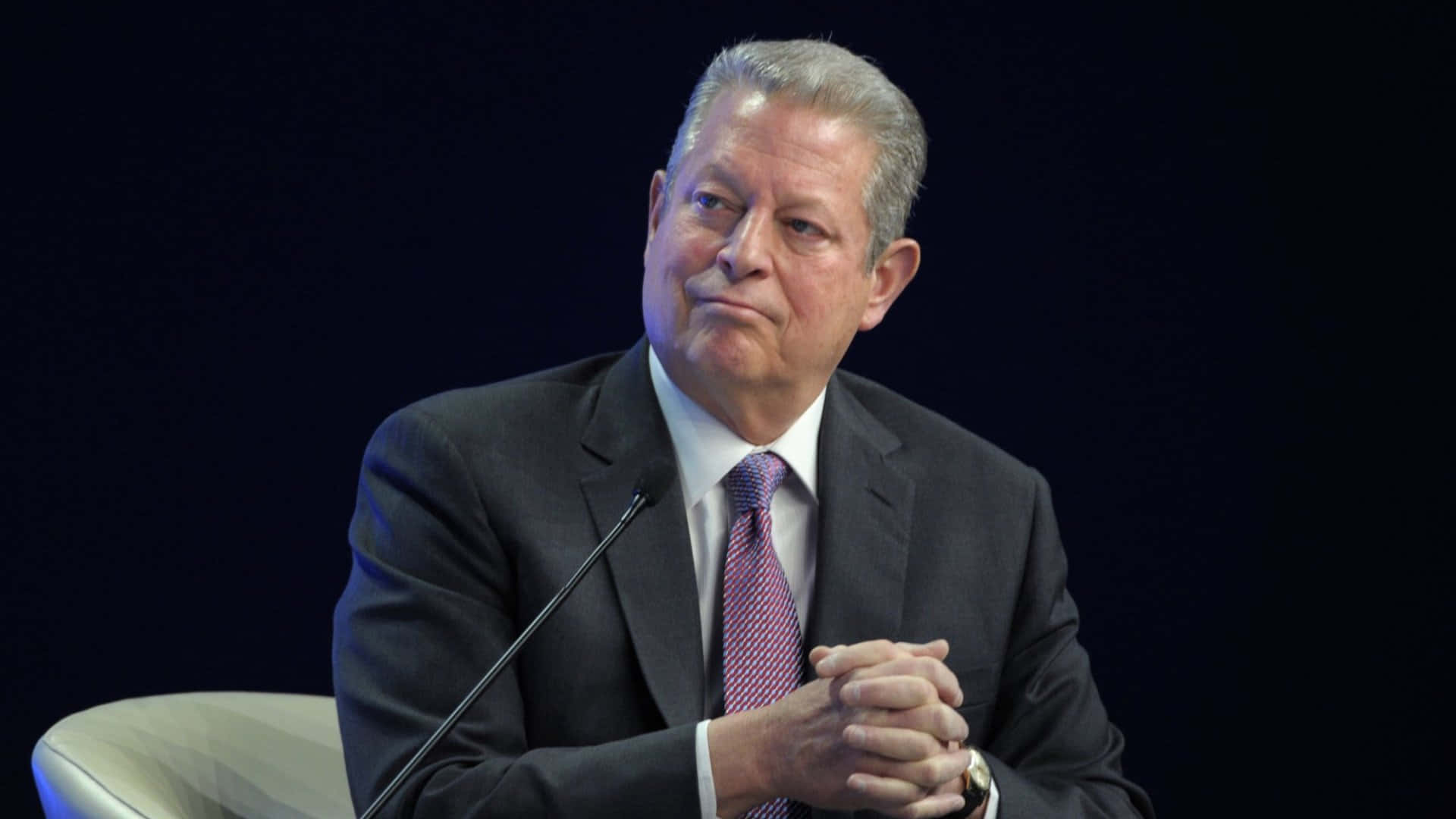 Al Gore Sitting With His Hands Clasped Background