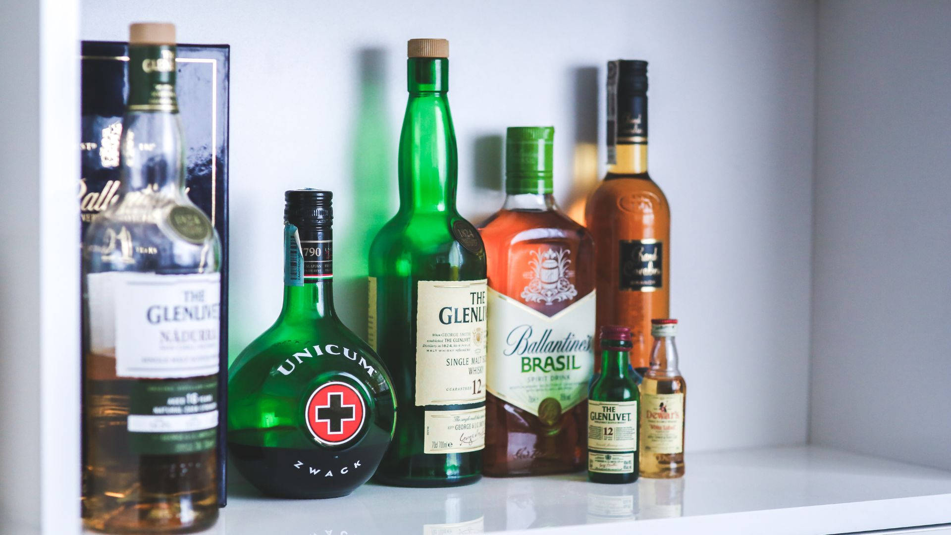 Alcohol Bottles Collection On White Shelf Background