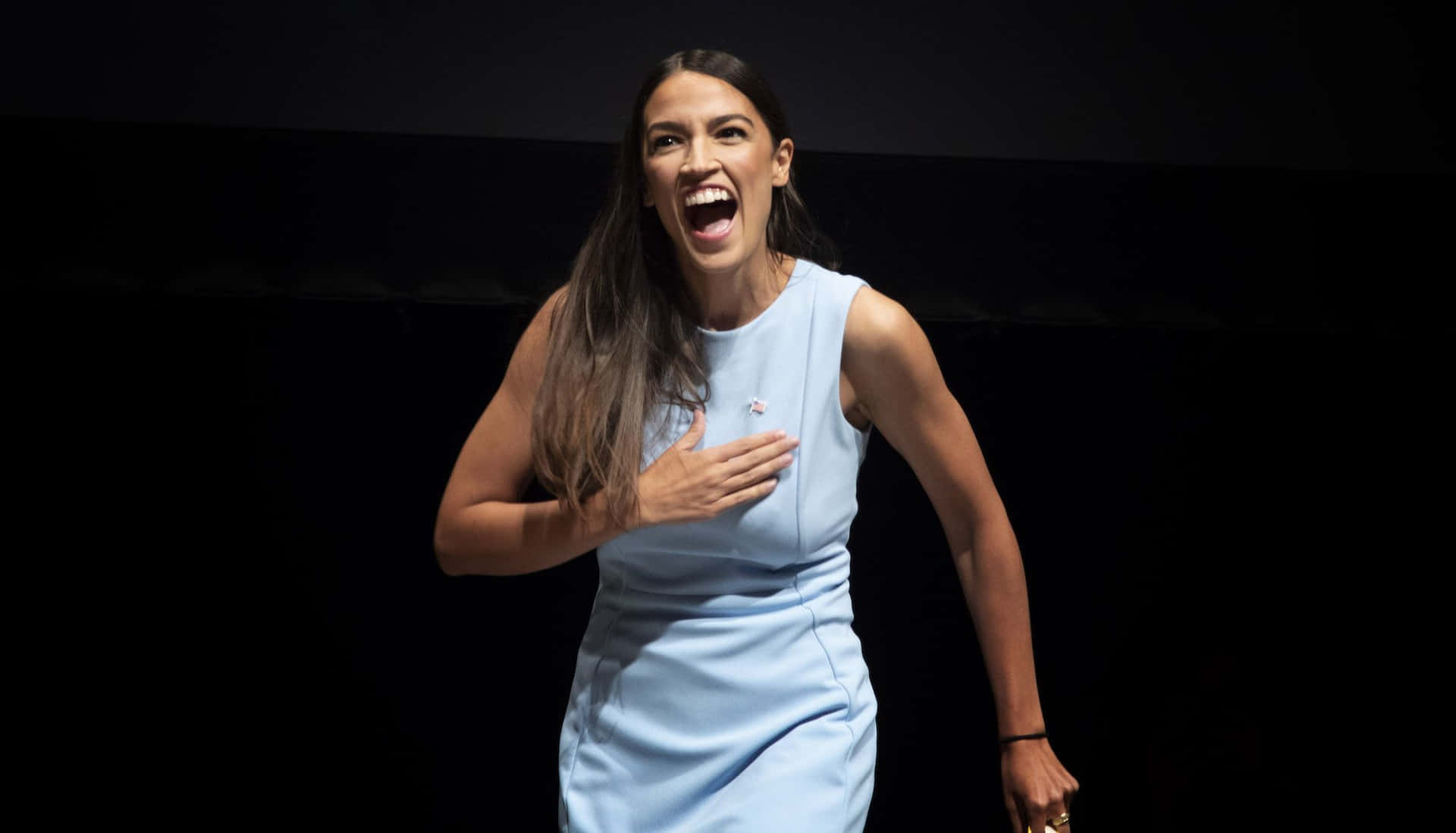 Alexandria Ocasio-cortez In Blue With Black Backdrop Background