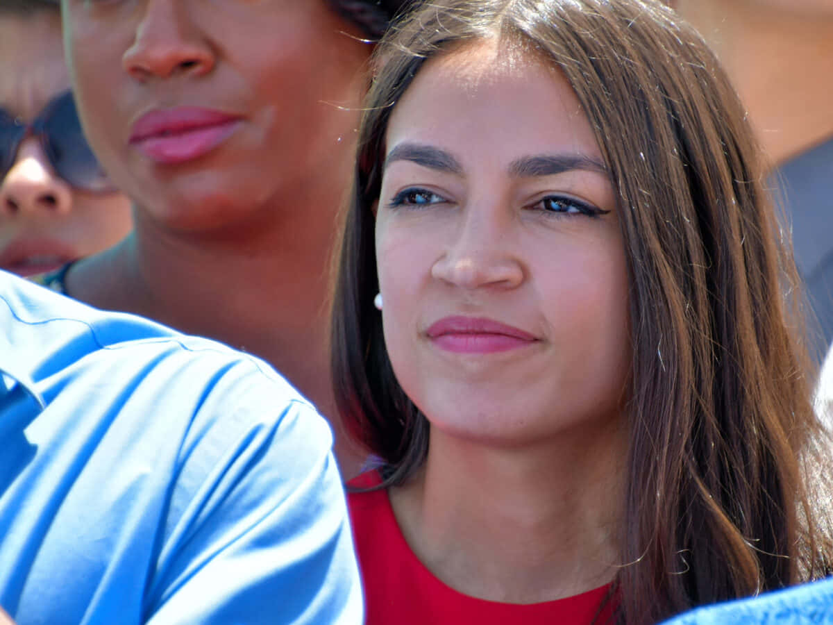 Alexandria Ocasio-cortez In Red Looking Towards Left Background