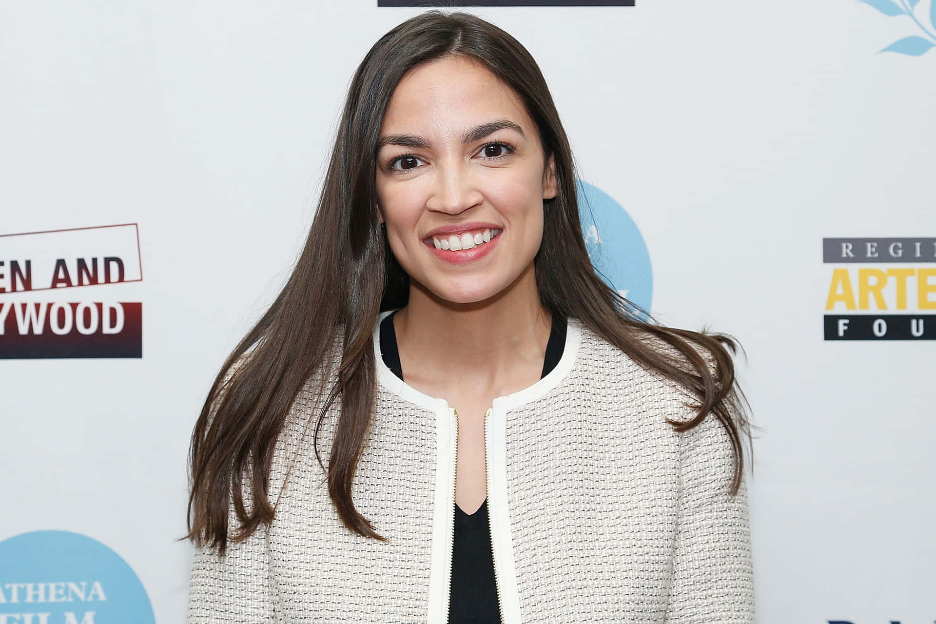 Alexandria Ocasio-cortez Smiling By White Backdrop Background