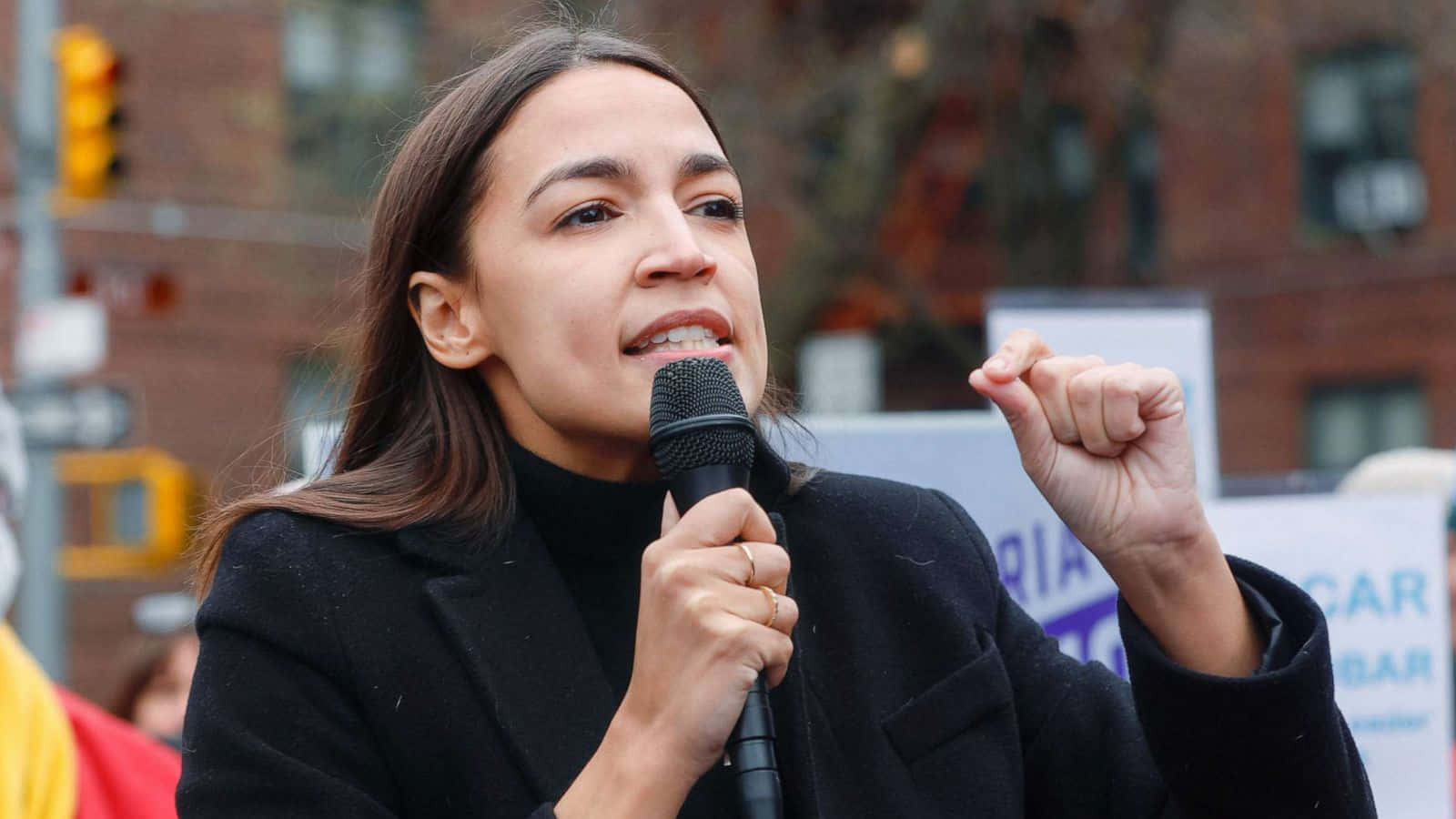 Alexandria Ocasio-cortez Talking Into A Microphone Background