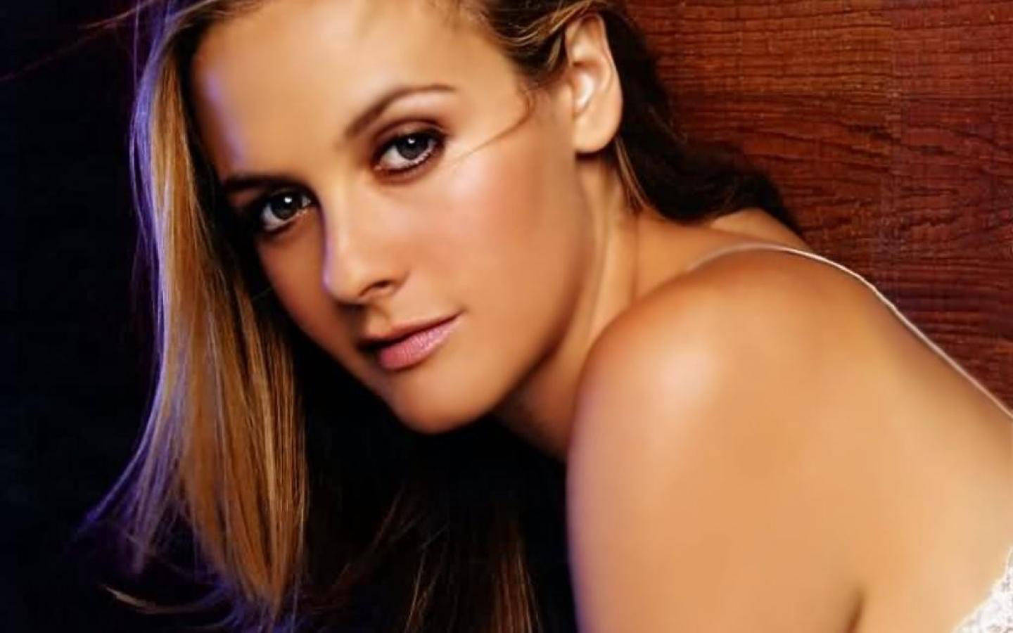 Alicia Silverstone Poses Against A Wooden Background