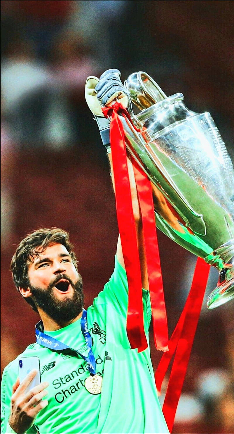 Alisson Becker Holding A Trophy And Medal In Triumph Background