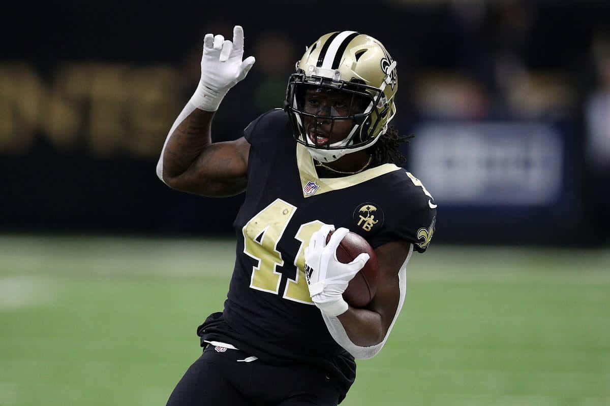 Alvin Kamara Showcasing His Elusiveness On The Football Field Background