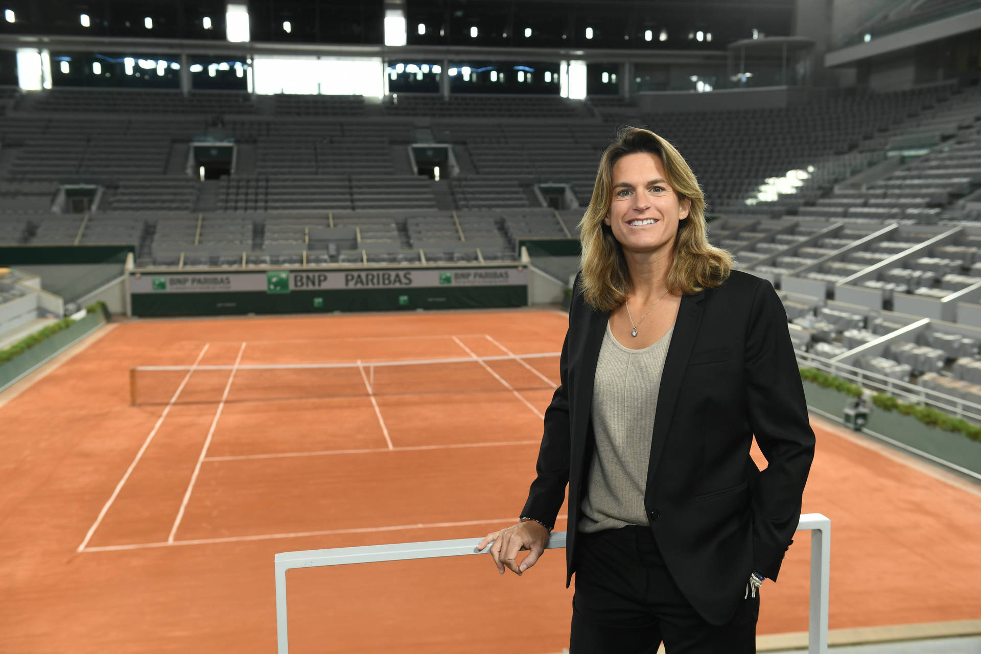 Amélie Mauresmo Posing Near Tennis Court Background