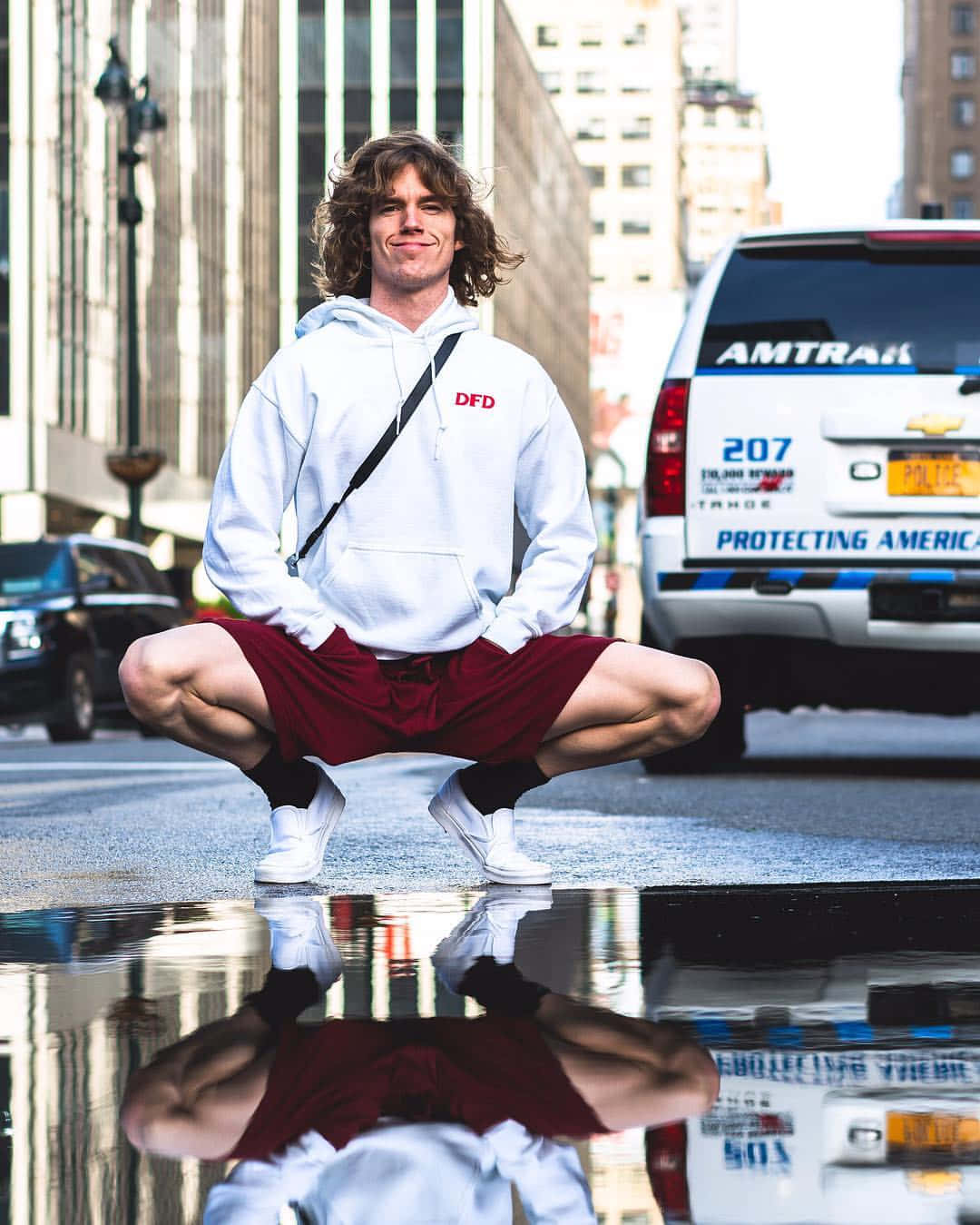 American Celebrity Danny Duncan Squatting Near Puddle Background