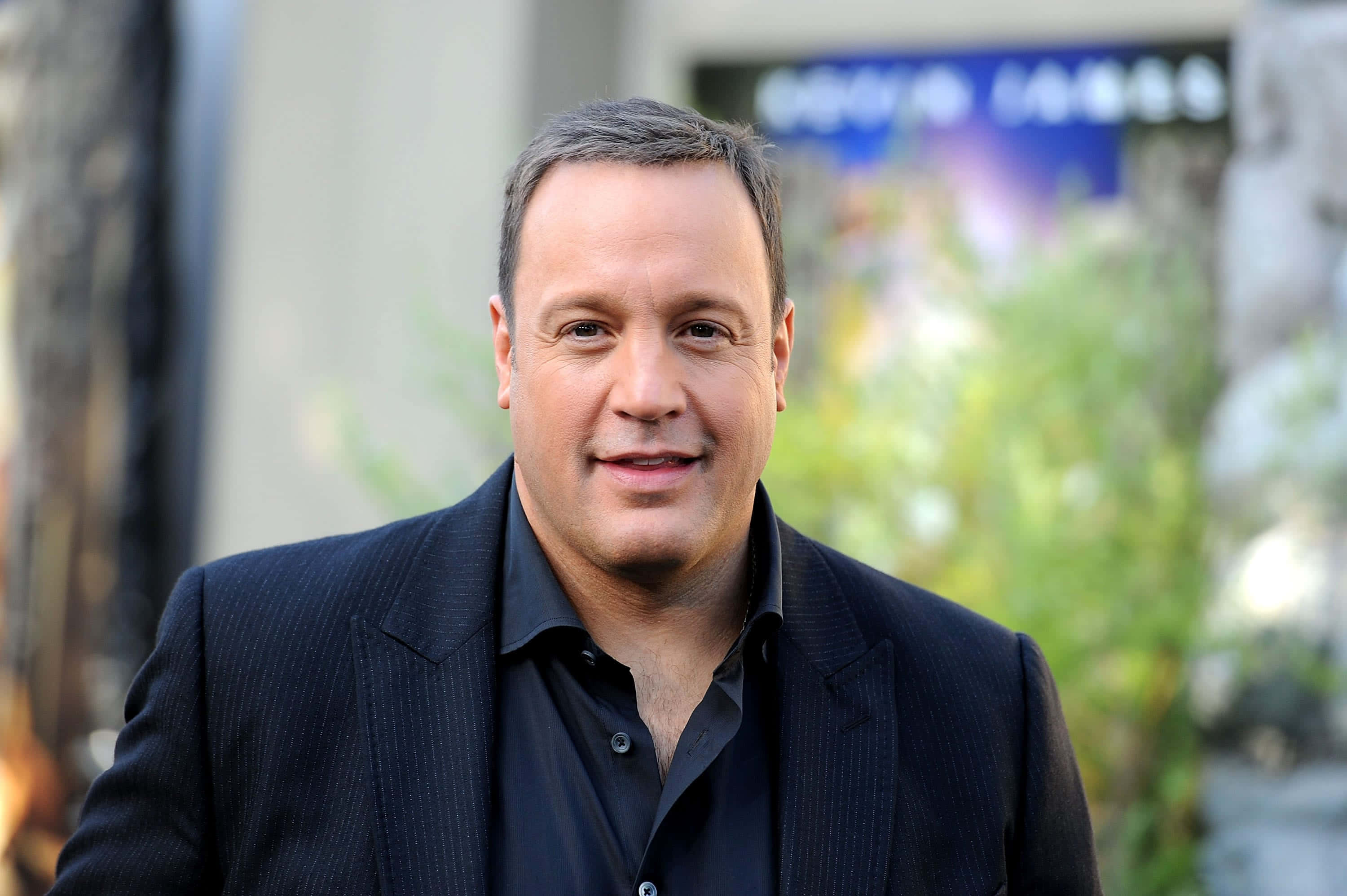 American Comedian Kevin James Exuding Confidence Background
