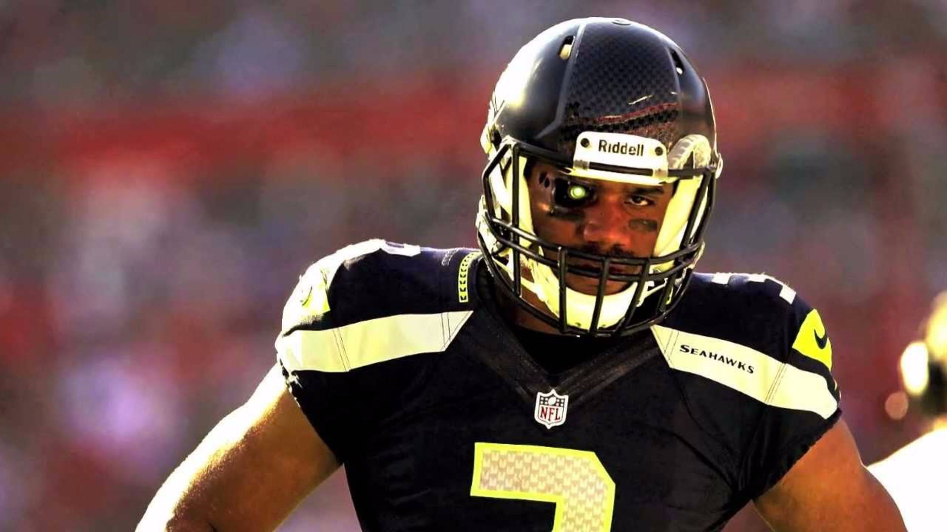 American Football Star Russell Wilson Poised In Helmet Background