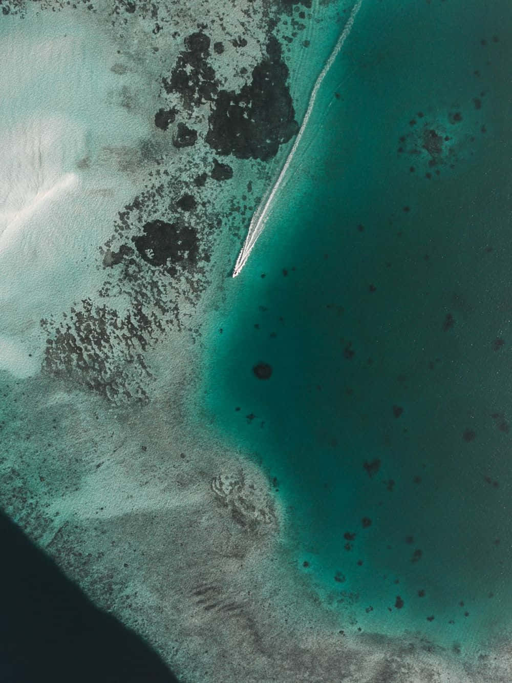 An Aerial View Of A Beach With A Boat In The Water Background