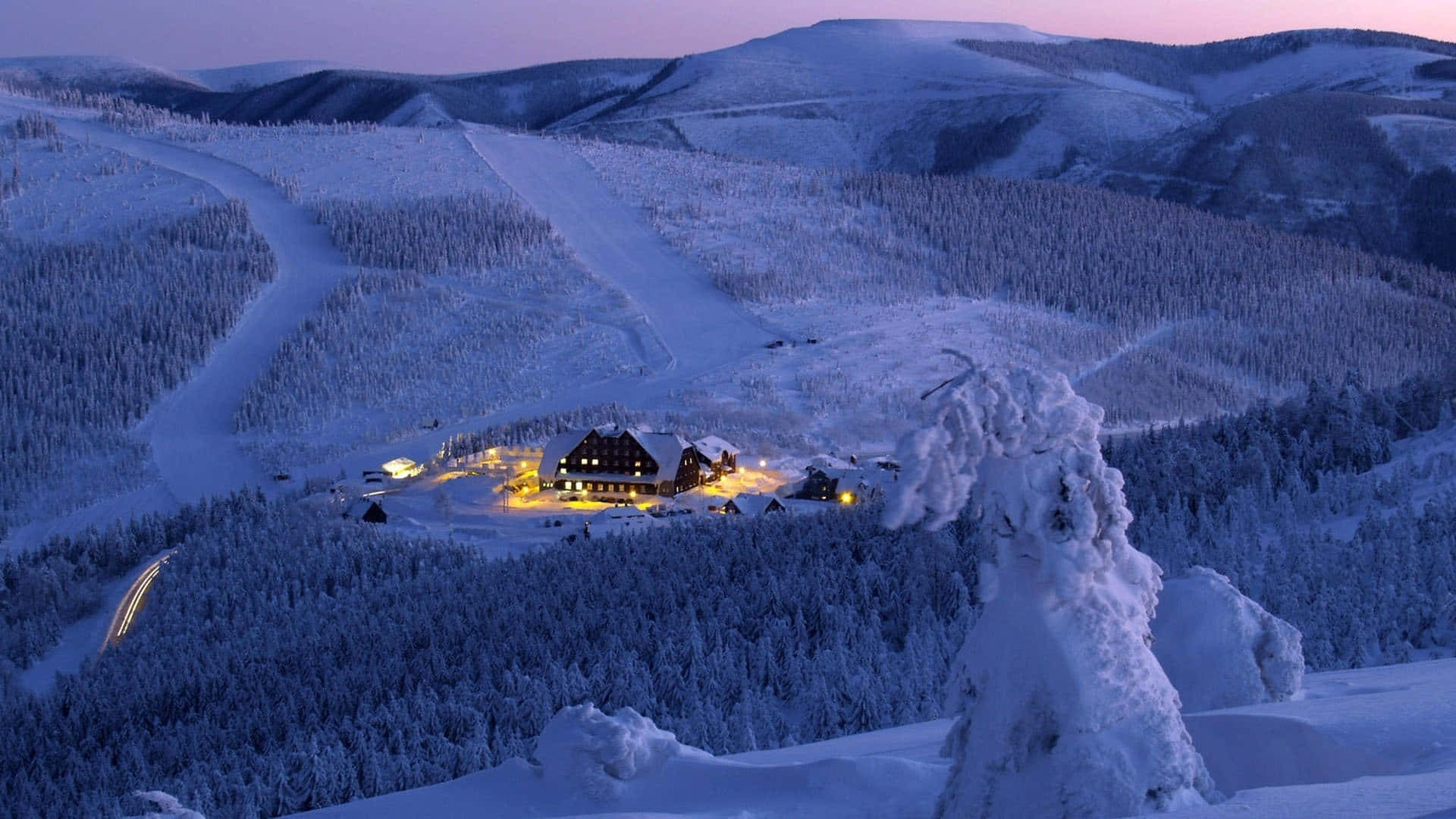 An Aerial View Of A Snow-covered Ski Mountain Surrounded By Pristine Nature Background